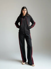 Person wearing a black and red tracksuit on a plain background