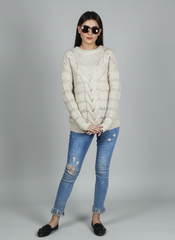 Model wearing Coastline's Ivory Cable Knit Sweater and sunglasses, with one hand near her face.