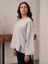 Model wearing the Cherie Top in Heather Grey by Coastline, highlighting its relaxed silhouette and distinctive sleeve detailing.