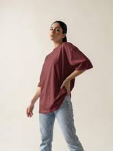 Model wearing Coastline's Coast Oversize Tee in Berry, showing its loose fit, dropped shoulders and wide short sleeves from a side angle.