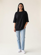 Model wearing Coastline's Coast Oversize Tee in Black, featuring a loose fit, crew neckline and wide short sleeves.