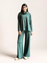 Model wearing Coastline’s Yula evergreen double-knit matching set with a high-neck top, long sleeves and wide-leg trousers.