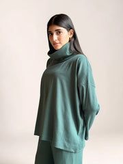 Side view of a model wearing Coastline’s Yula evergreen double-knit co-ord top, showing its high neckline, loose sleeves and relaxed drape.