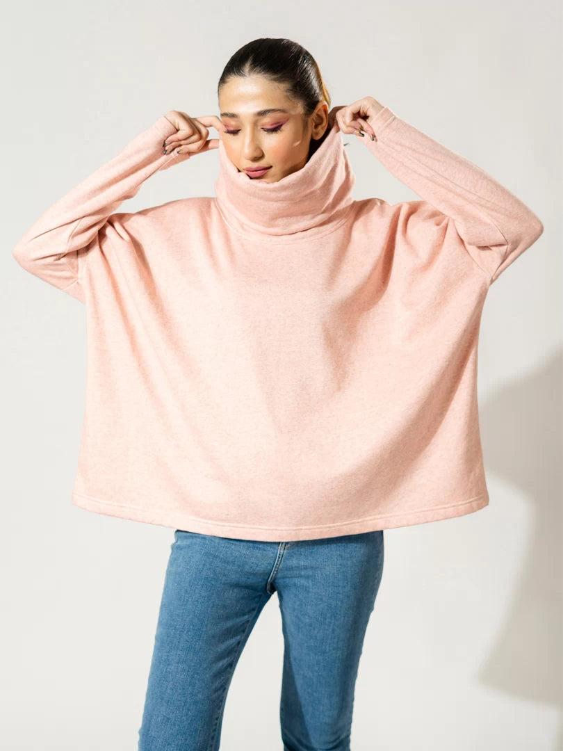 Model wearing the Elkin high-neck sweatshirt in Heather Pink, holding its folded collar and showing the loose, boxy fit.