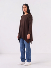 Model wearing Coastline's Florens Flare Top in Chocolate Brown, showing its long sleeves, gently flared hem and relaxed longline cut.