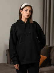 Front view of the Lynn Essential Black hoodie, showing its oversized fit, extended body length and dropped shoulders.
