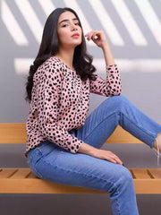 Side view of the Heather Pink animal print sweatshirt as the model sits on a wooden bench wearing blue jeans.
