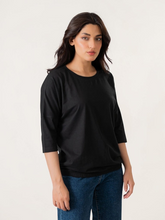 Model wearing Coastline's Rylee Batwing Sleeve Top in Black, featuring loose batwing sleeves, a round neckline and an elasticated hem.