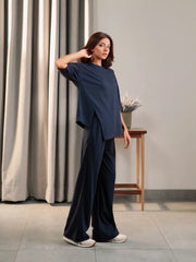 Side view of the Sorelle Oxford Blue matching set showing the oversized top and wide-leg trousers, with one hand raised to the head.