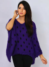 A woman wearing a purple, oversized, fluffy sweater with a high neck and long sleeves.
