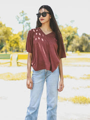 Model wearing Coastline's Beach Club Oversized Top in Rosewood Red, featuring dropped shoulders and a loose fit in an outdoor fashion shoot.