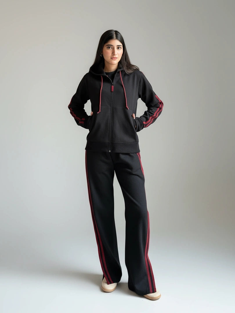 Person wearing a black and red tracksuit on a plain background