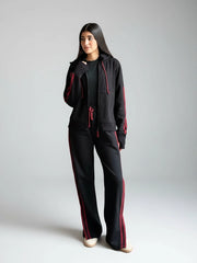 Person wearing a black tracksuit with red accents on a plain background
