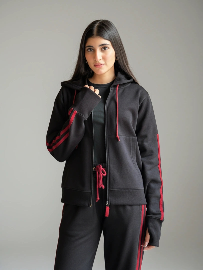 Person wearing a black hoodie with red accents on a gray background