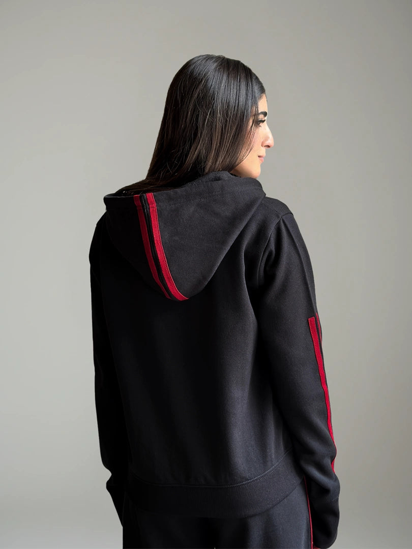 Person wearing a black hoodie with red accents on a gray background