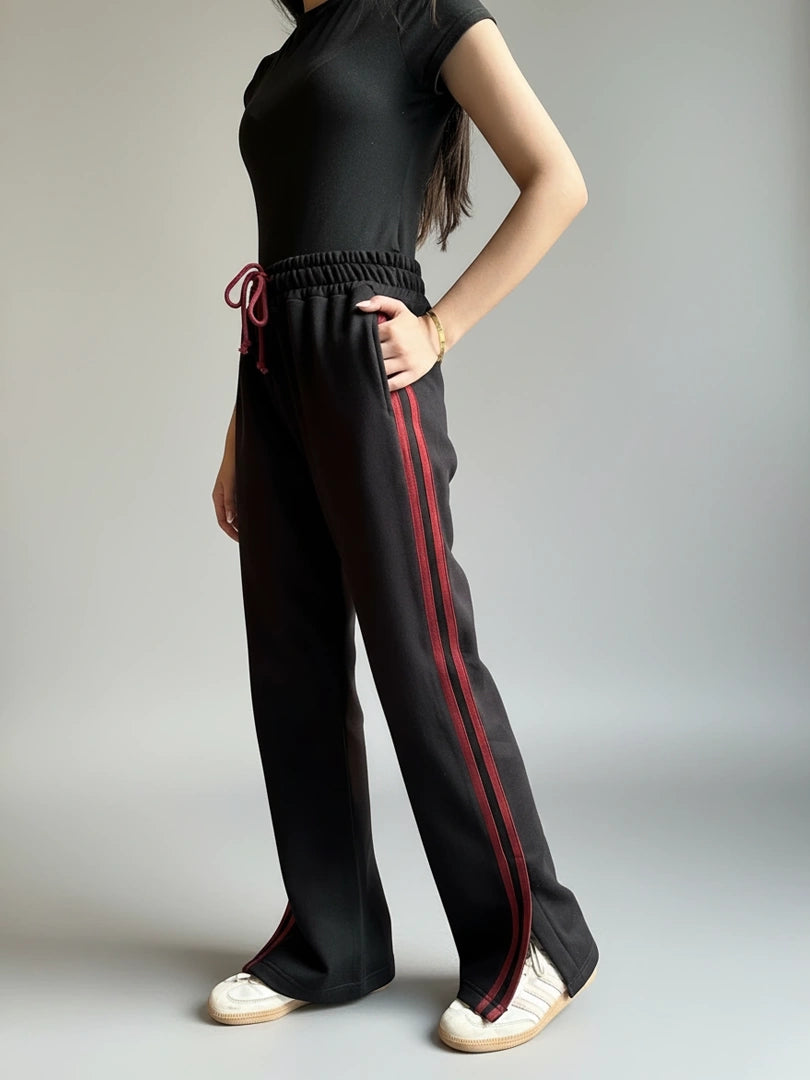 Person wearing black pants with red stripes on a gray background