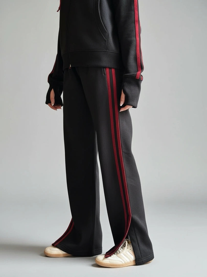Person wearing black tracksuit with red stripes on a gray background