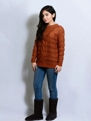 Woman wearing a brown sweater and blue jeans with black boots on a white background