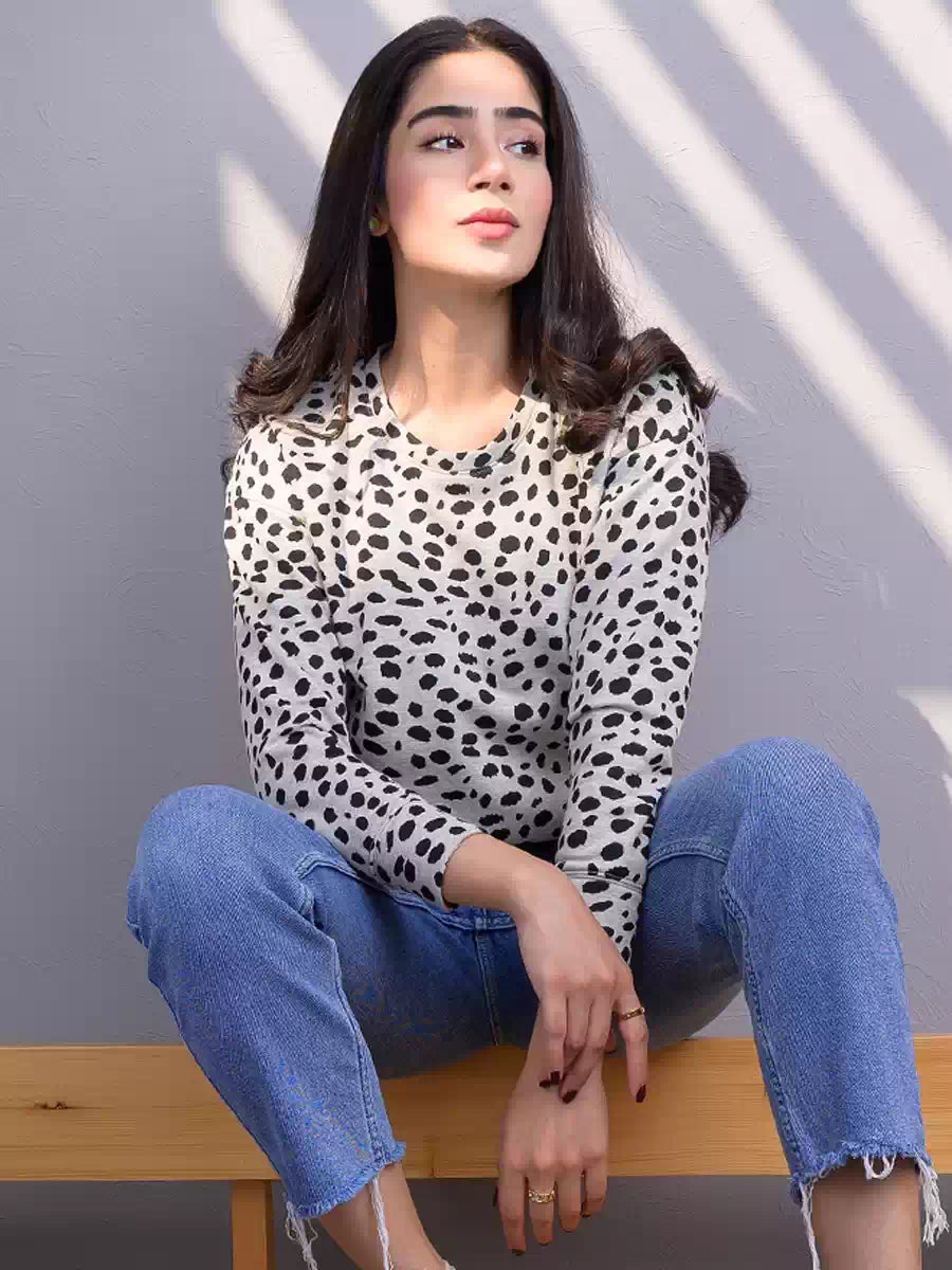 Front view of the Heather Grey animal print sweatshirt as the model sits on a wooden bench, showing its black spotted pattern and relaxed fit.