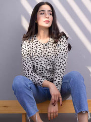 Front view of the Heather Grey animal print sweatshirt as the model sits on a wooden bench, showing its black spotted pattern and relaxed fit.