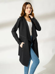 Model wearing the Ashley black draped overlayer with one hand at her hip, showing the open front and asymmetric hemline.