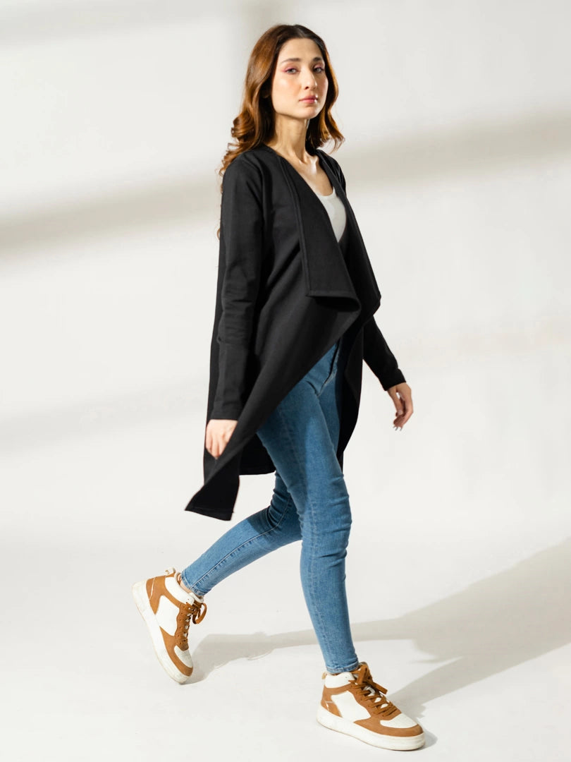 Model walking in the Ashley black long overlayer, showing the flowing front panels over blue jeans.