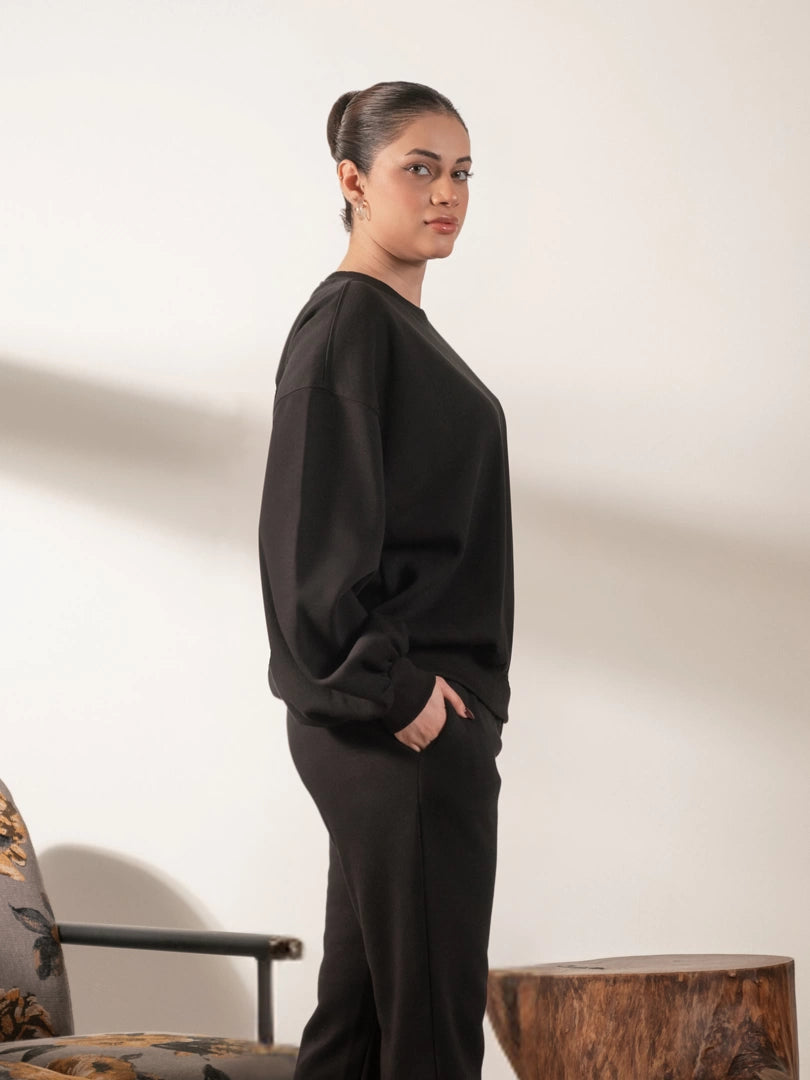 Side view of the Barlow oversized black sweatshirt highlighting its loose fit and rounded balloon sleeve shape.