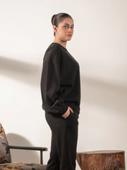 Side view of the Barlow oversized black sweatshirt highlighting its loose fit and rounded balloon sleeve shape.