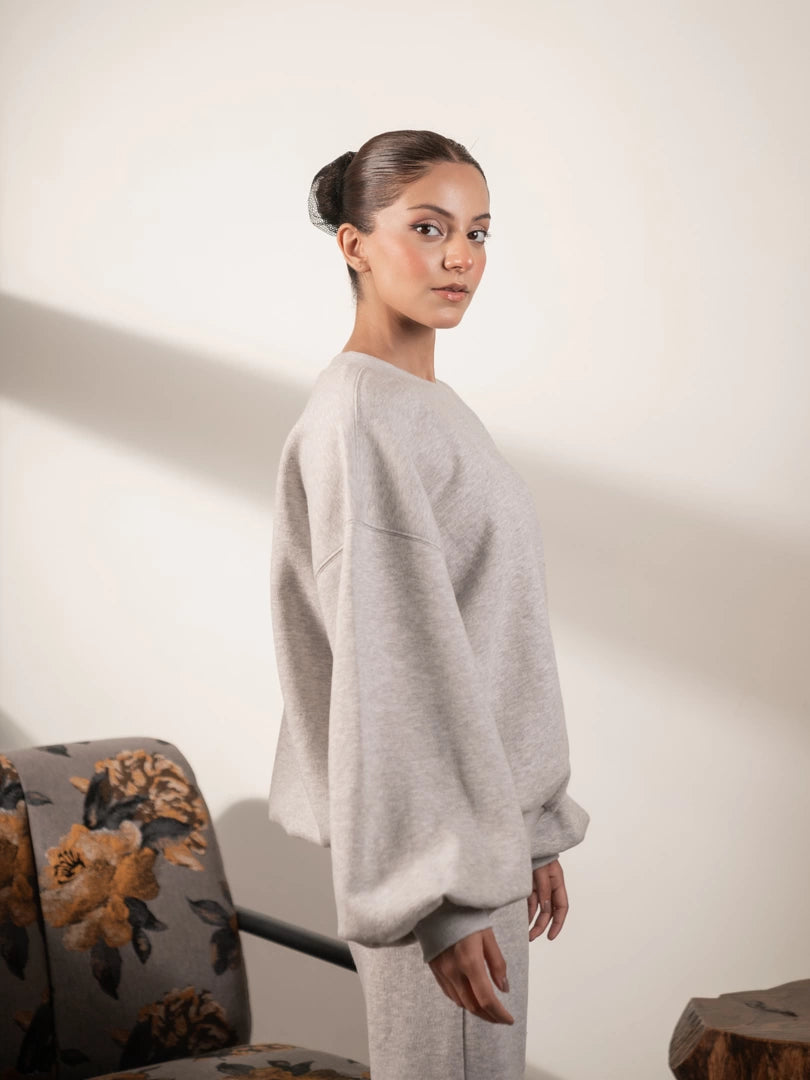 Three-quarter view of the Barlow oversized Heather Grey sweatshirt, showing its rounded balloon sleeves and relaxed side fit.