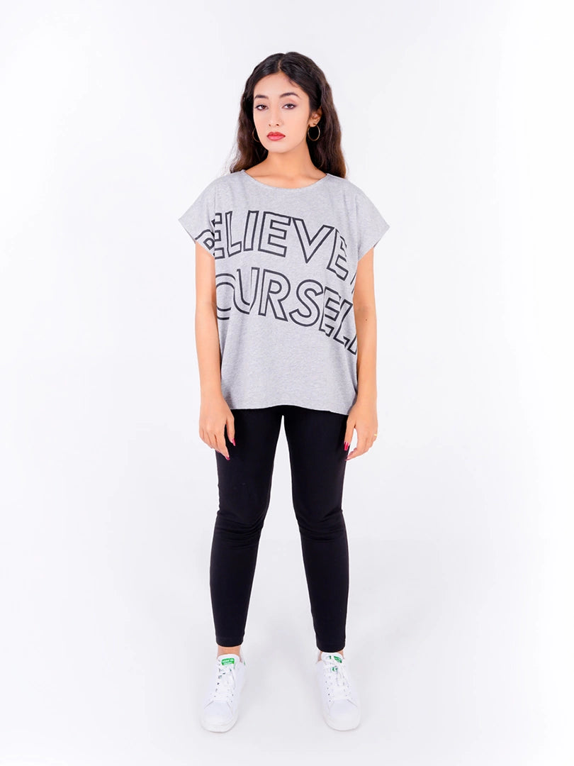 Full front view of Coastline's Believe In Yourself Top in Ash Grey, showing the oversized black typography print and straight, loose-fitting hem.