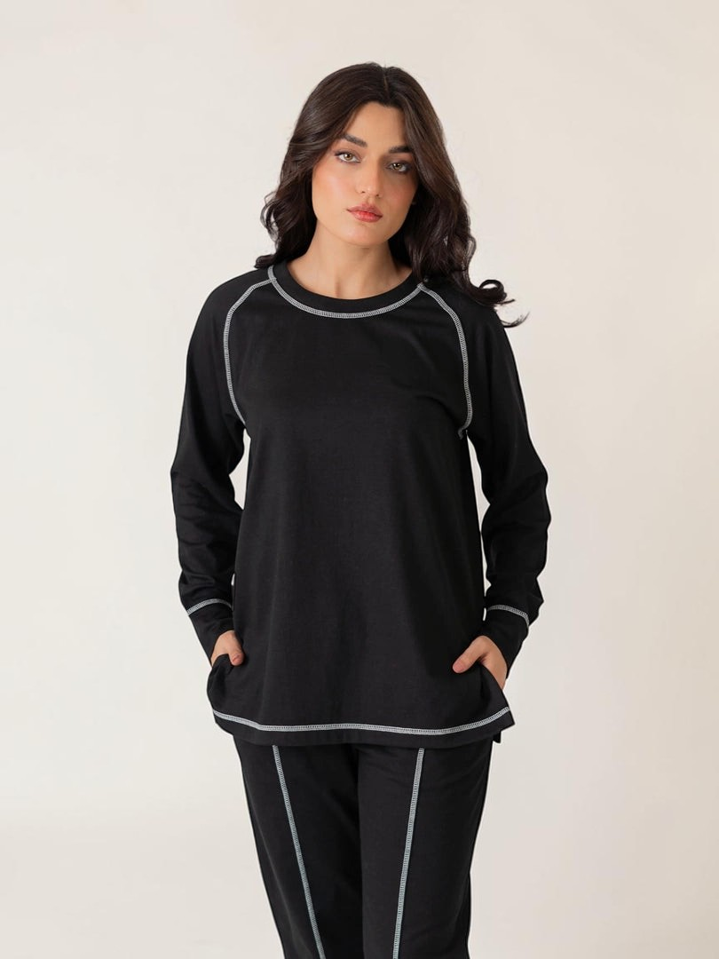 Model wearing the Berlin Black two-piece set with raglan sleeves, distinctive top-stitching and relaxed-fit trousers.