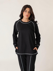 Model wearing the Berlin Black two-piece set with raglan sleeves, distinctive top-stitching and relaxed-fit trousers.