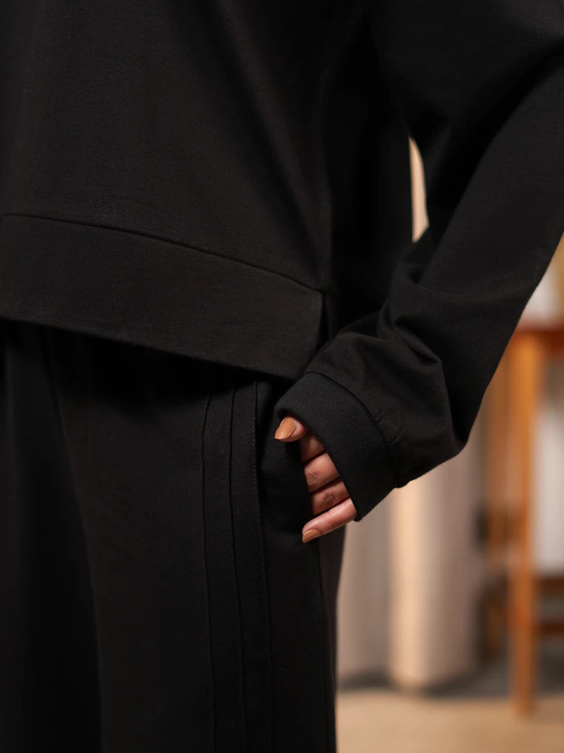 Close-up of the Brooklyn black top showing the sleeve opening and hem above the matching trousers.