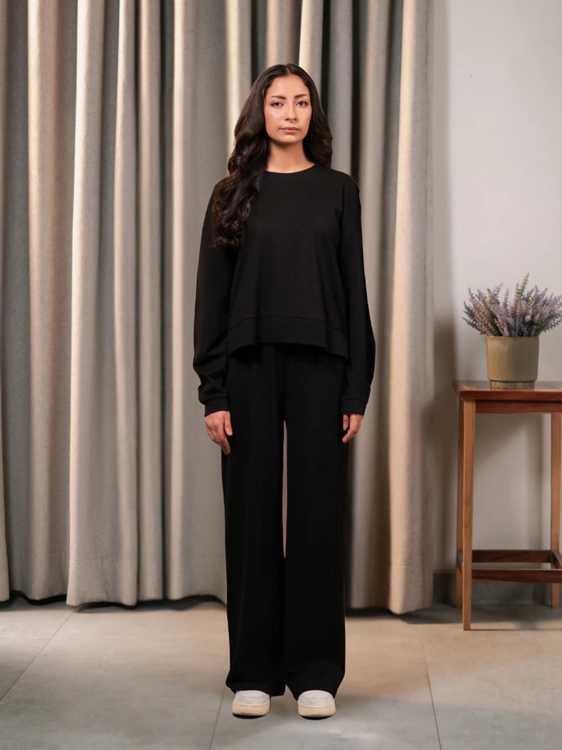 Model standing in the Brooklyn black two-piece summer set with a boxy top and wide-leg trousers, with both arms at her sides.