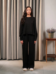 Model standing in the Brooklyn black two-piece summer set with a boxy top and wide-leg trousers, with both arms at her sides.