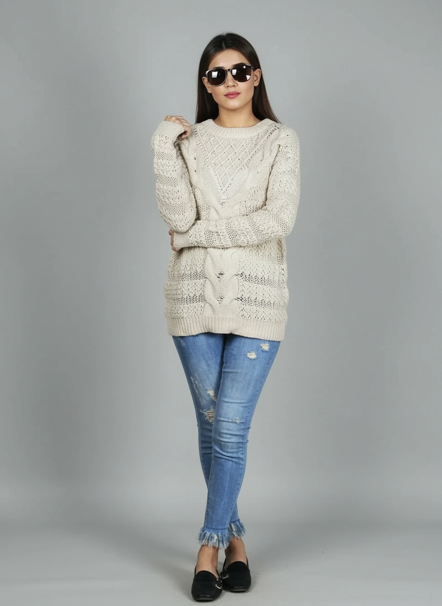 Full-length view of Coastline's Ivory Cable Knit Sweater styled with blue distressed jeans and sunglasses.