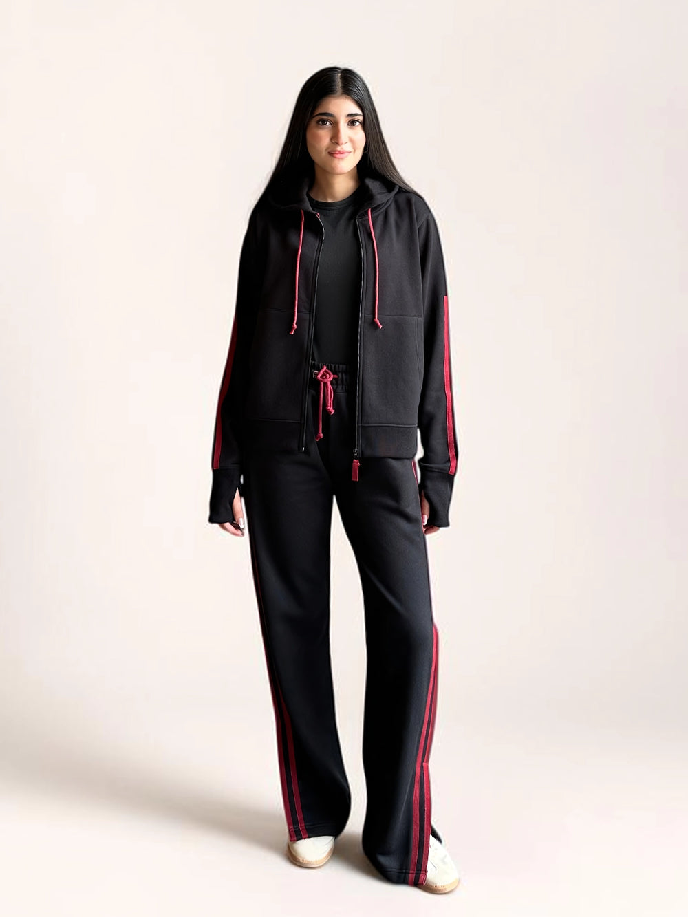 Front view of a model wearing Coastline’s black and red hoodie set, showing the relaxed jacket fit and full-length wide-leg trousers.