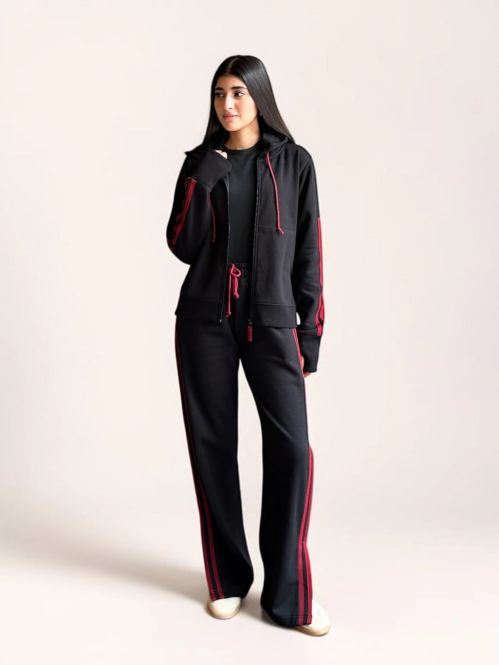 Full-length view of a model wearing Coastline’s black and red co-ord set, showing the zip-front hoodie and relaxed wide-leg trousers.