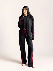 Full-length view of a model wearing Coastline’s black and red co-ord set, showing the zip-front hoodie and relaxed wide-leg trousers.