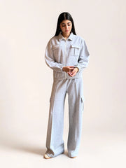 Model wearing Coastline’s heather gray fleece matching set with her hands near the waistband, showing the jacket’s gathered hem and wide-leg trouser fit.