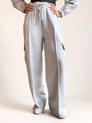 Model wearing Coastline’s heather gray fleece cargo sweatpants with one hand on her hip, showing the gathered waistband and loose wide-leg silhouette.