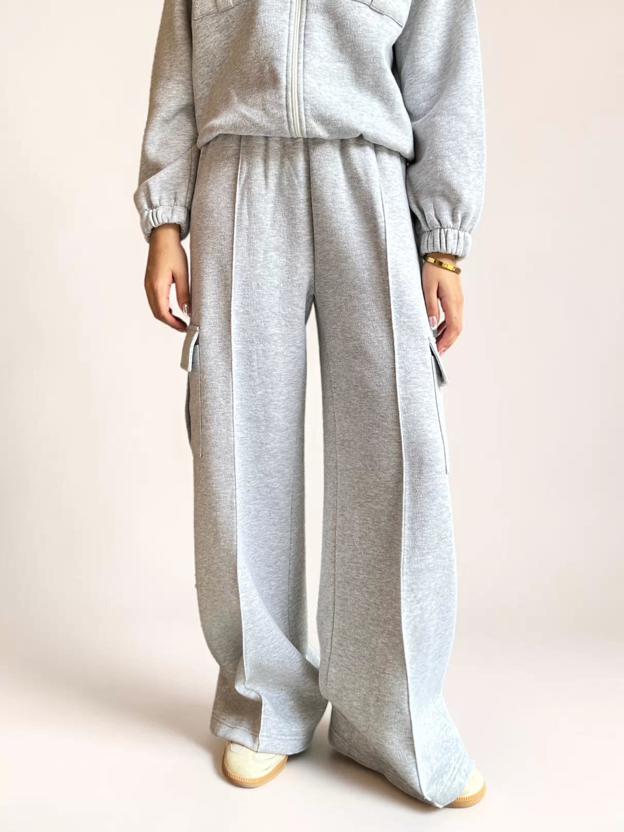 Model wearing Coastline’s heather gray fleece cargo sweatpants with an elasticated waistband, wide legs and thigh pockets.
