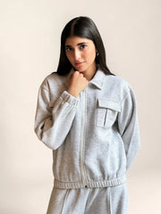 Close-up of a model wearing Coastline’s heather gray fleece jacket, showing the collar, front zipper, flap chest pockets and gathered hem.
