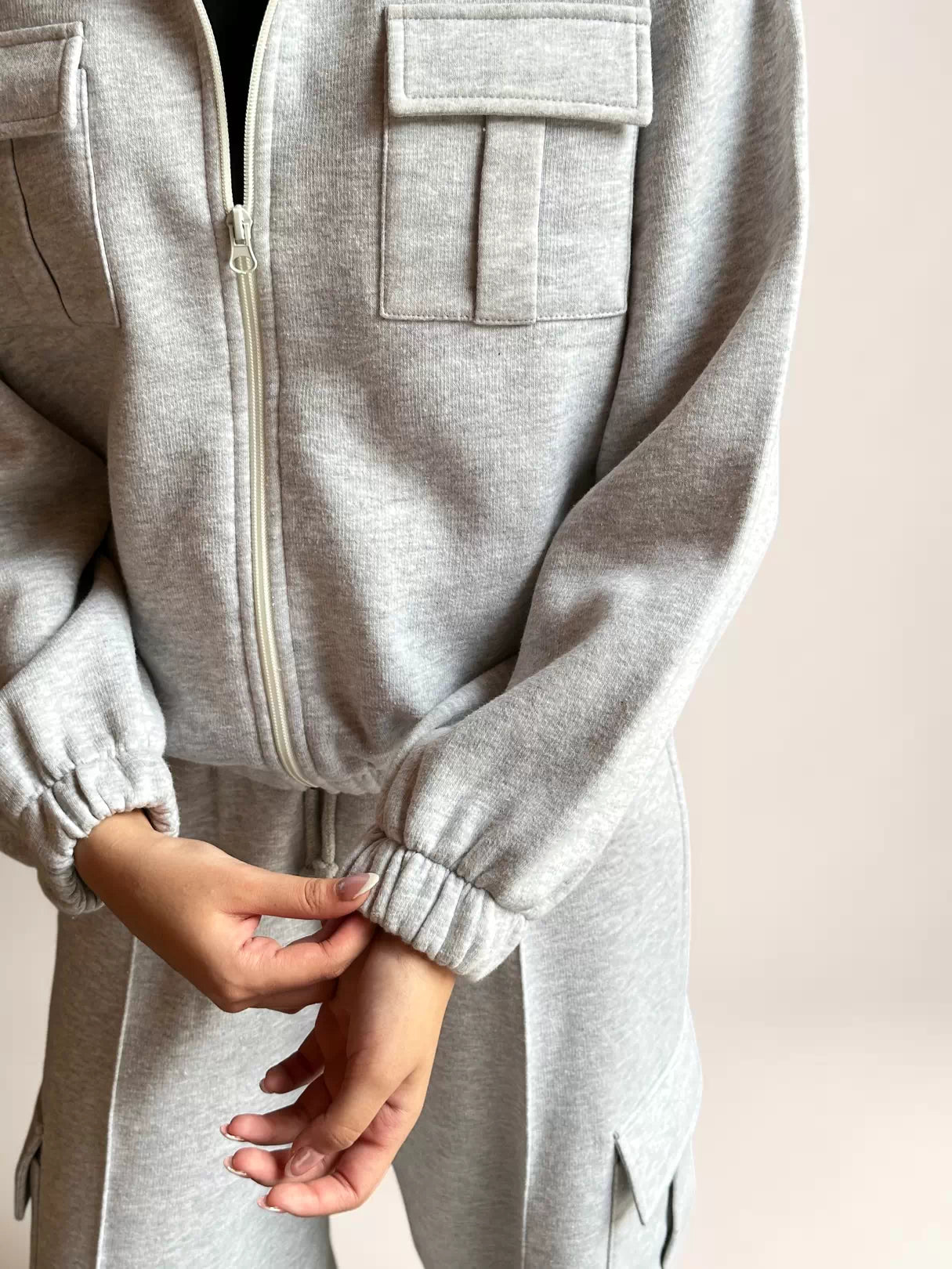 Close-up of Coastline’s heather gray fleece jacket, showing a flap chest pocket, front zipper and ribbed sleeve cuffs.