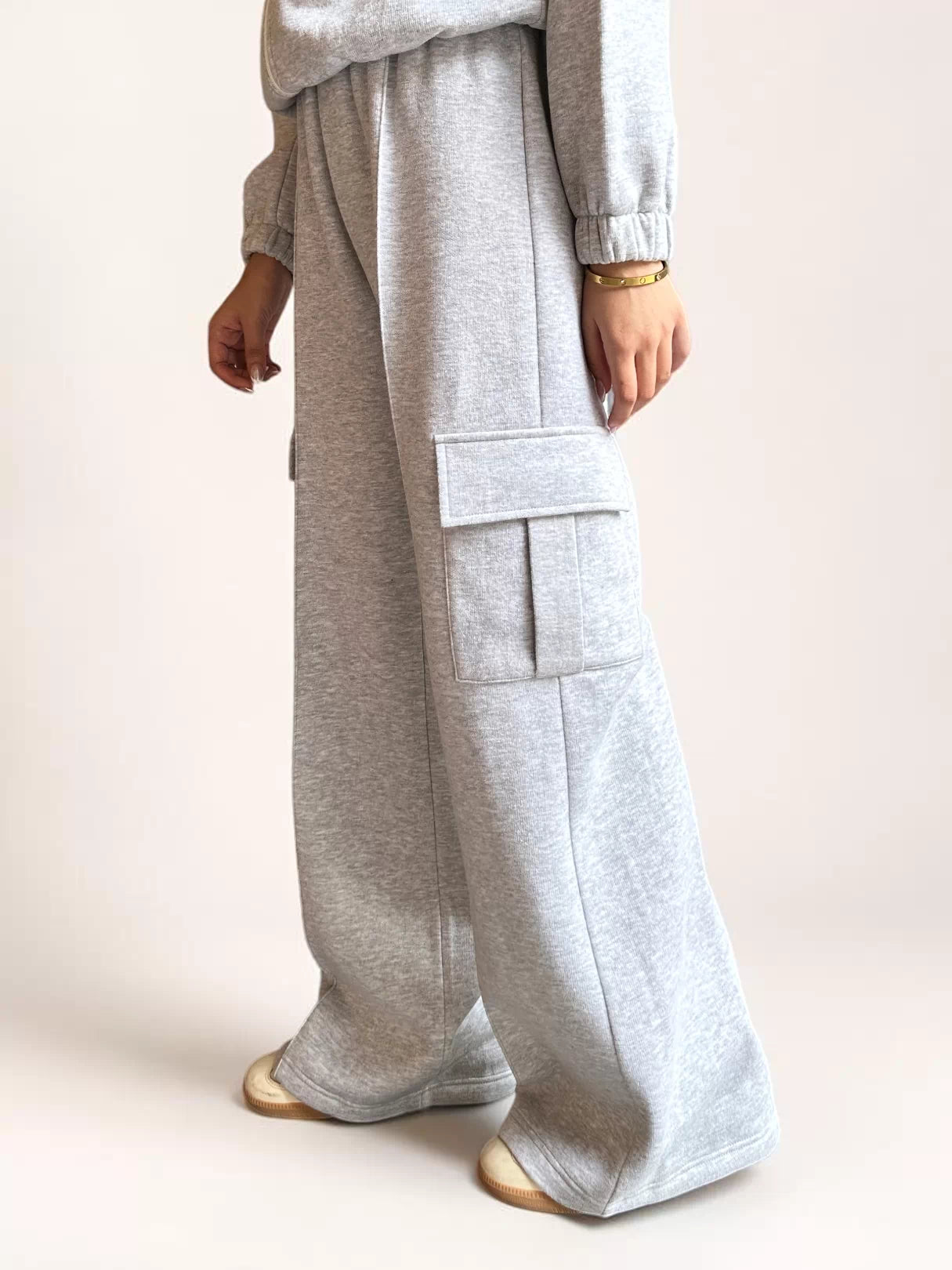 Angled view of a model wearing Coastline’s heather gray fleece cargo trousers, showing the side pocket and relaxed, full-length fit.