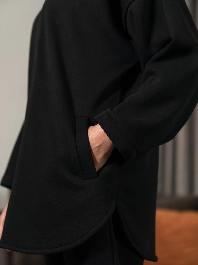 Close-up of a front welt pocket on the Darya black oversized hoodie, with the model placing one hand inside.
