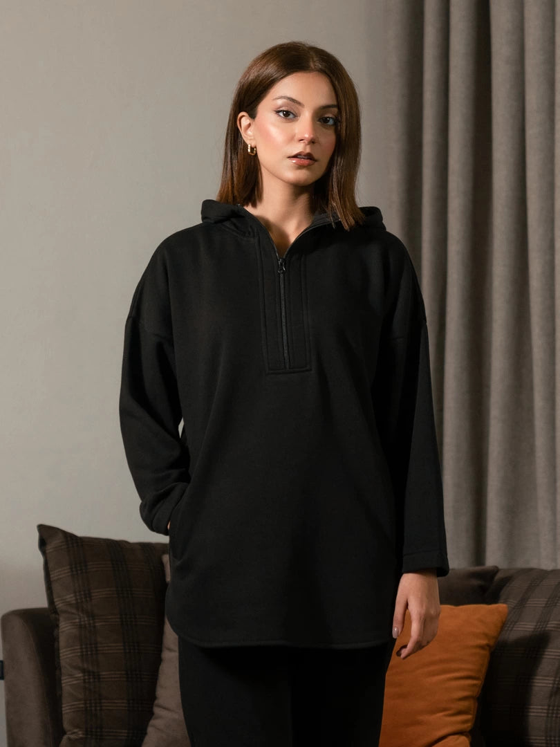 Closer front view of the Darya black oversized hoodie showing its dropped shoulders, extended zipper and front pockets.