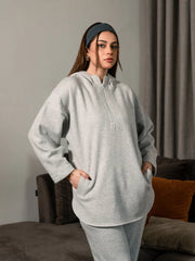 Closer view of the Darya Heather Grey oversized hoodie showing the extended zipper and front pockets, with both hands in the pockets.