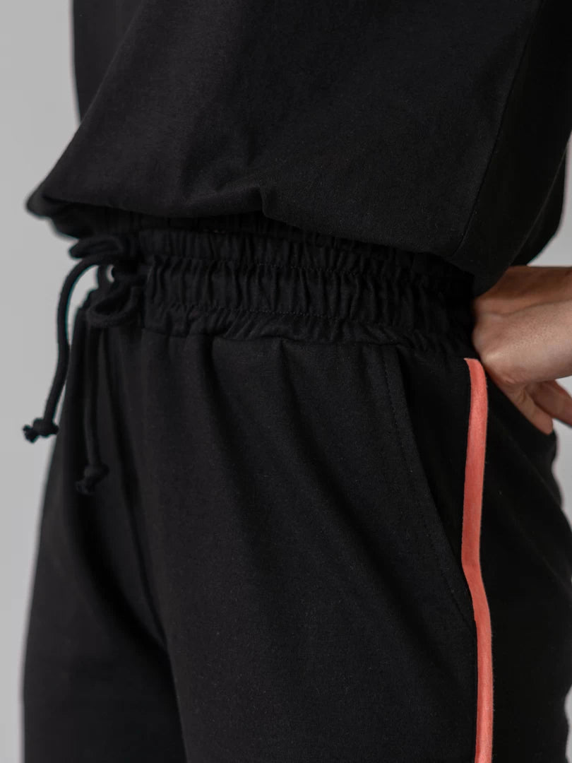 Close-up of Ellioti black wide-leg trousers showing the contrast side detail and elasticated waistband
