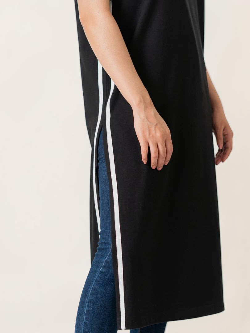 Close-up of the Eve black maxi dress showing its deep side slit finished with white contrast tape detailing.